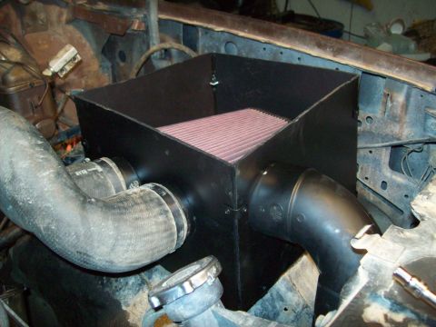 1985 Ford Bronco - Aftermarket air intake system installed in the engine bay of a vehicle.
