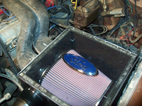 1985 Ford Bronco - Close-up of an aftermarket air filter assembly with a Ford emblem in an engine bay.