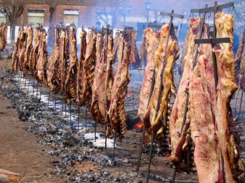 1986 Ford Bronco - Large quantities of meat are being slow-cooked outdoors over an open fire.