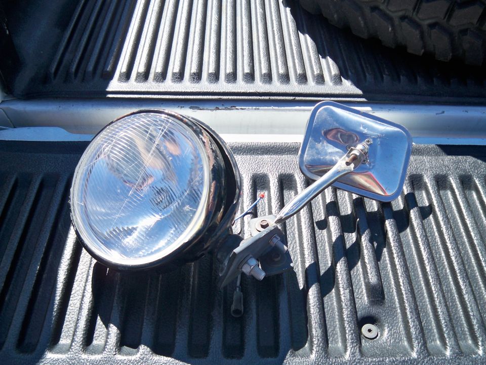 Headlight and chrome side mirror on a black truck bed liner