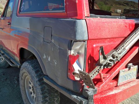 1985 Ford Bronco - This 1985 Ford Bronco shows damage to its rear quarter panel and taillight, with a Hi-Lift jack mounted for off-road use.