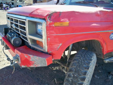 1985 Ford Bronco - This red Ford truck's front end displays a winch and a heavily damaged hood and fender.