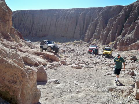 1985 Ford Bronco - Off-road vehicles navigate a canyon trail under a clear blue sky.