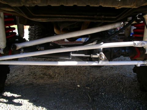 1979 Ford Bronco - The underside of a vehicle shows modified steering and suspension components.