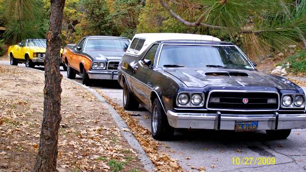 Dark blue 1973 Ford Ranchero with a white camper shell, front view