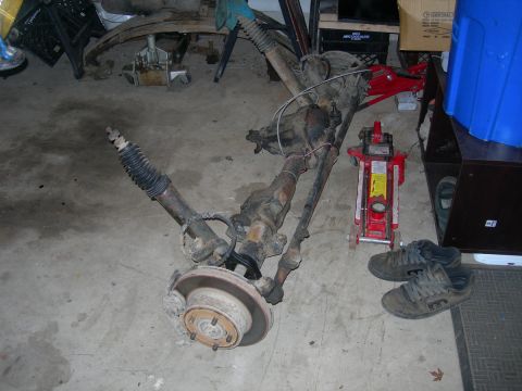 1991 Jeep Wrangler - A disassembled Jeep front axle assembly is shown, likely for repair or modification, with tools and personal items nearby.