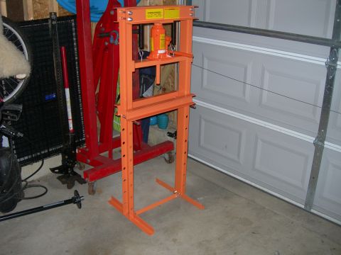 1991 Jeep Wrangler - An orange hydraulic press stands in a garage, with a red engine hoist to its left.