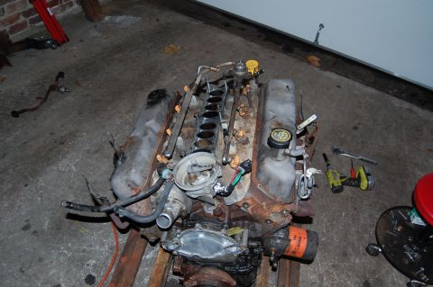 1994 Ford Bronco - A V8 engine, likely removed from a vehicle, sits on a concrete floor with tools nearby.