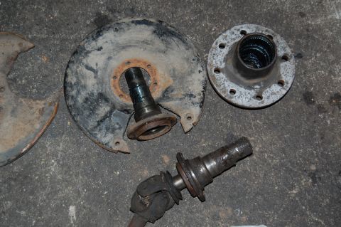 1994 Ford Bronco - Various axle components, including a spindle, hub, and backing plate, are laid out on a concrete surface.