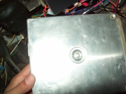 1985 Ford Bronco - A close-up view of an engine control unit, showing its metallic casing and connected wires.