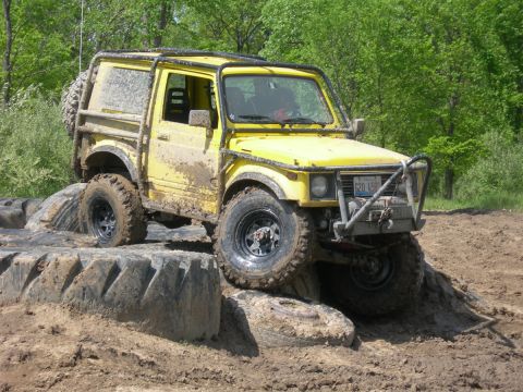 1991 Jeep Wrangler - This yellow off-road vehicle is equipped with a roll cage and is shown navigating a challenging mud course.