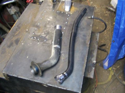 1995 Ford C-350 (Centurion Conversions) - Two fuel system components, a filler neck and a hose, are shown on a workbench.