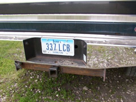 1995 Ford C-350 (Centurion Conversions) - Close-up of a vehicle's rear bumper, showing an Iowa license plate and a trailer hitch attachment.