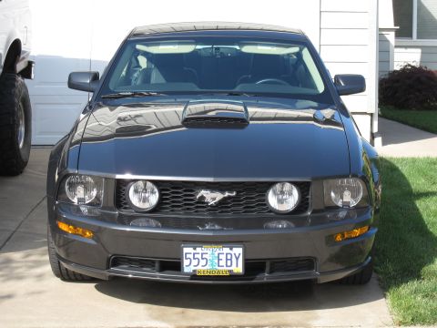 1996 Ford Bronco - Front view of a dark gray Ford Mustang parked in front of a garage.