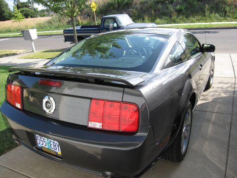 1996 Ford Bronco - Rear view of a dark gray Ford Mustang coupe with a spoiler and GT badging.