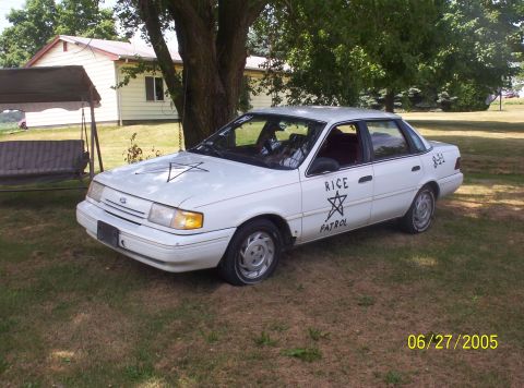 1982 Oldsmobile Cutlass - White sedan with custom decals and symbols parked in a grassy yard.
