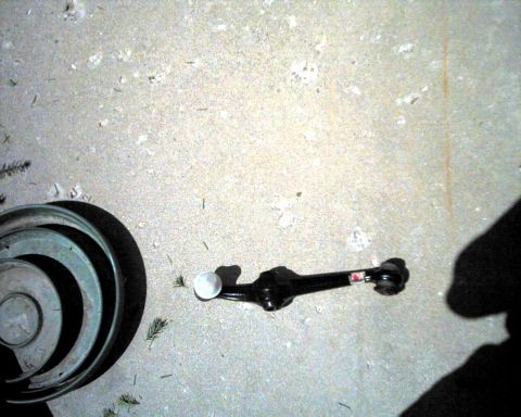 1990 Ford Taurus - Automotive suspension part and metal rings on a concrete surface. The part has a sticker with text.