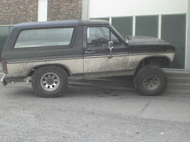 Two-tone black and tan Ford Bronco with a camper shell, seen from the side