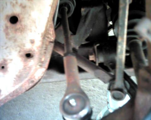 1990 Ford Taurus - Close-up view of vehicle suspension components, showing rust and mechanical parts.