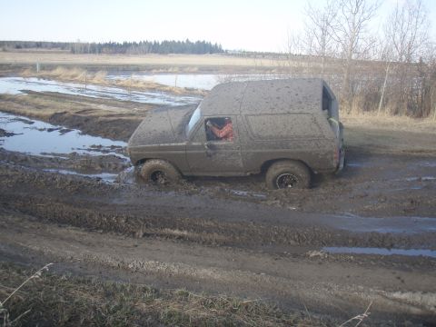 1985 Ford Bronco - This SUV is deeply stuck in thick mud, with water pooling around it.