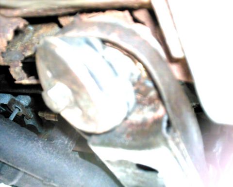 1990 Ford Taurus - This image shows a close-up view of a rusty exhaust system component, possibly a muffler or catalytic converter, with a white protective co…