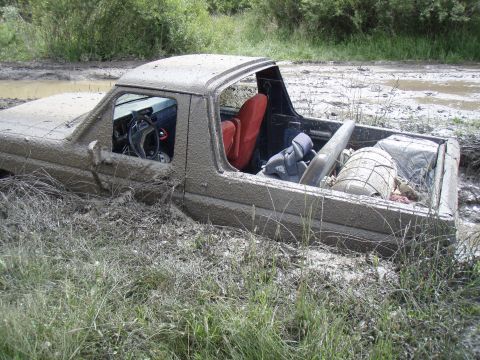 1985 Ford Bronco - This SUV is deeply stuck in mud, with its interior and cargo area partially submerged.