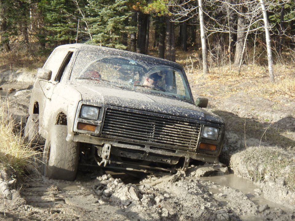 Mud-covered SUV navigating a rough, muddy terrain