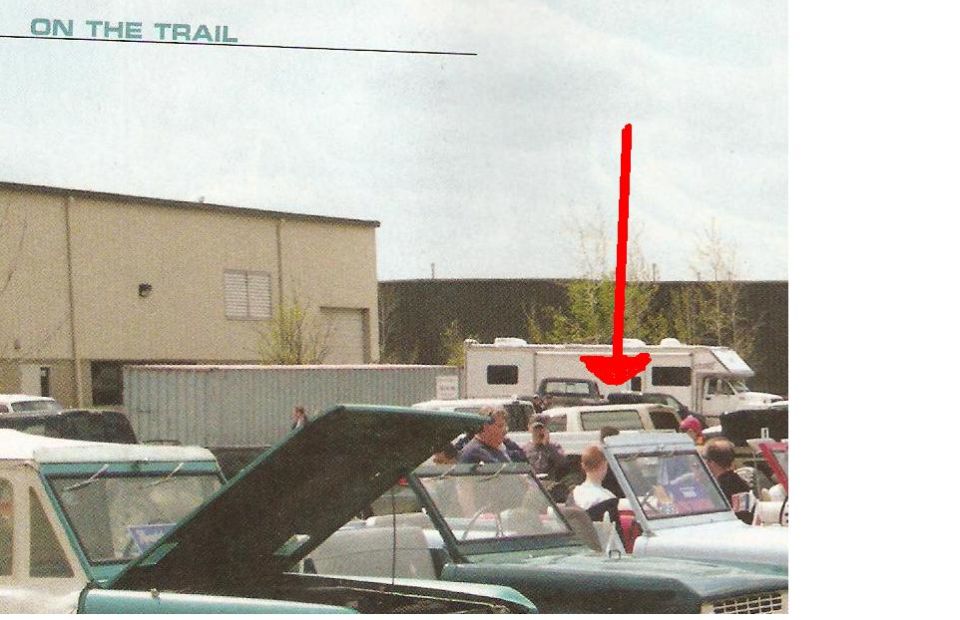 Green Ford Bronco with hood up, parked near other vehicles and RVs