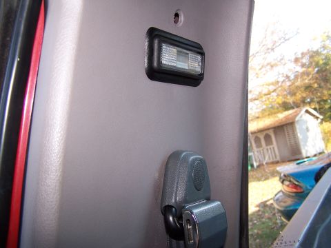 1991 Jeep Comanche - Close-up of an interior light and seatbelt buckle against a gray panel.