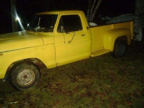 1991 Ford Bronco - A yellow pickup truck is parked outside at night, with its side profile visible against a dark background.