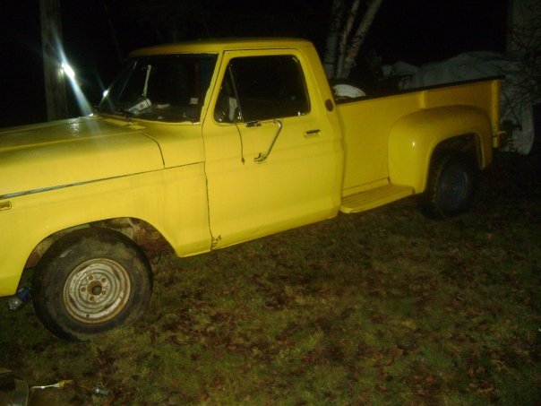 Yellow pickup truck parked on grass at night. Side view shows the cab and bed
