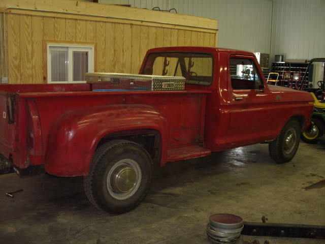 Red pickup truck with a toolbox in the bed, parked inside a garage