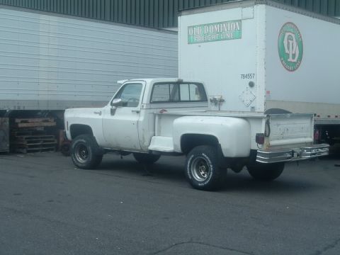 1991 Ford Bronco - A white pickup truck is parked next to a large semi-trailer with 'Old Dominion Freight Line' visible on its side.