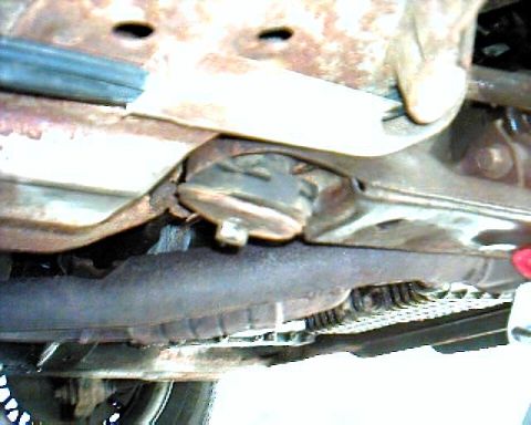 1990 Ford Taurus - Close-up view of a vehicle's undercarriage, revealing rusted parts and exhaust system.