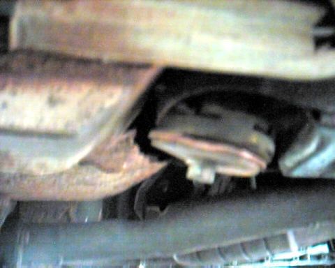 1990 Ford Taurus - Close-up view of the underside of a vehicle, focusing on exhaust pipes and suspension elements.