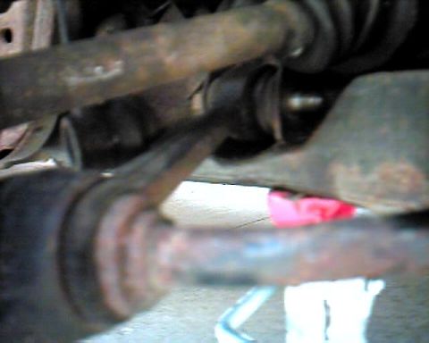 1990 Ford Taurus - Close-up view of heavily rusted automotive suspension parts, likely from the front of a vehicle.