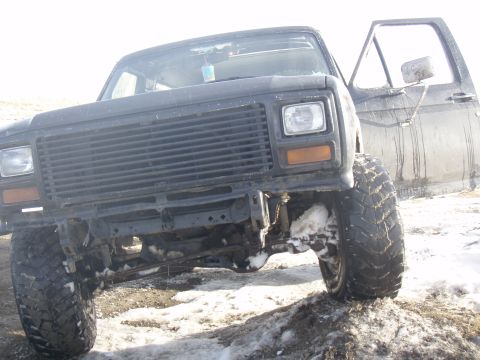 1985 Ford Bronco - This lifted Ford truck, likely from the early 1980s, is parked outdoors with snow on the ground and its driver's door ajar.