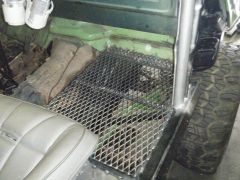 1978 Ford Bronco - The interior of a vehicle shows a custom metal floor grate and roll bar, with a seat visible.