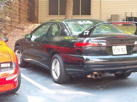 1998 Ford Taurus - The rear of a black coupe is visible, parked next to another vehicle.