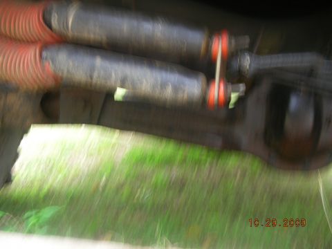 1991 Ford F-150 - Underside view of vehicle suspension parts, including shocks with orange bellows and part of the axle.