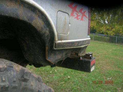 1991 Ford F-150 - The rear of a silver 1991 Ford F-150 pickup truck is visible, showing a 4x4 decal and a black bumper.