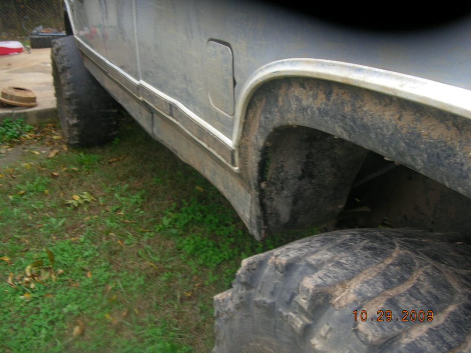 Side view of a lifted truck with large tires and a fuel door