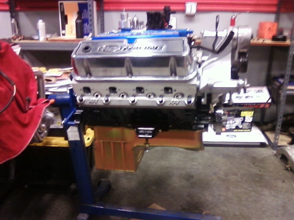 V8 engine with Ford Racing valve covers mounted on a blue engine stand in a garage