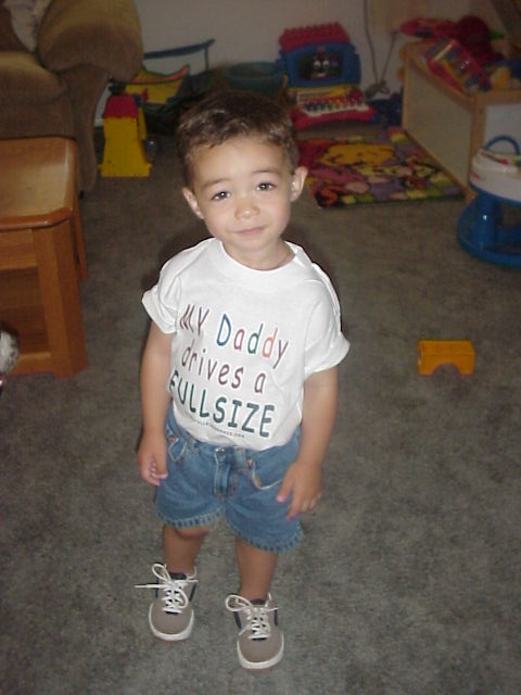1989 Ford Bronco - A young child stands in a room with toys, wearing a shirt that states "MY Daddy drives a FULLSIZE".