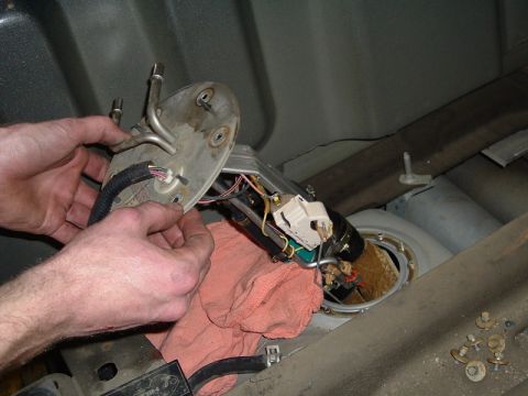 2007 Ford Mustang - A mechanic works on removing a fuel pump assembly from a vehicle's fuel tank.