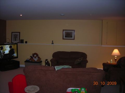 1984 Ford Bronco - A basement living area is shown with furniture and a television displaying a program.