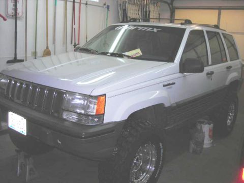 1996 Jeep Grand Cherokee - White 1996 Jeep Grand Cherokee on jacks in a garage, showing its front quarter.