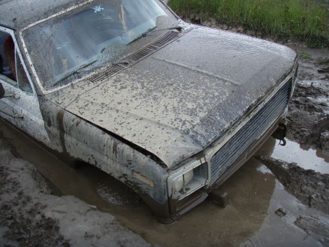 1985 Ford Bronco - This pickup truck is stuck deep in the mud, with only its front end visible above the mire.