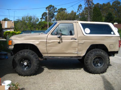 1989 Ford Bronco - This 1989 Ford Bronco features a two-tone paint scheme and oversized tires, suggesting off-road modifications.