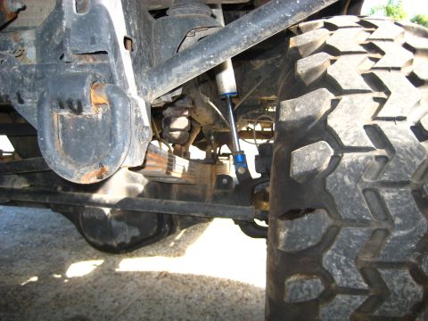 1989 Ford Bronco - Rear suspension and tire detail of an off-road vehicle, showing leaf springs and a shock absorber.